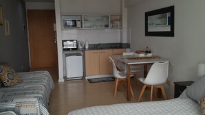 Un espacio habitable compacto con kitchenette, comedor y cama.