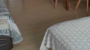 Una cocina moderna con armarios blancos, microondas y cafetera. Hay una mesa de comedor con sillas y una lámpara colgante roja sobre ella.