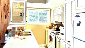 A kitchen with white cabinets, a wooden ceiling, and a decorative starfish hanging on the wall.