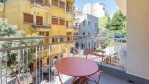 A balcony with a round table and chairs, overlooking a street with parked motorcycles and a building with balconies. - Tulip 2BR Apartment In Gemmayze (Bayrut)