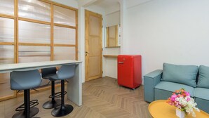 A modern living space with a dining area, a red refrigerator, a sofa, and a coffee table with flowers. - Tulip 2BR Apartment In Gemmayze (Bayrut)