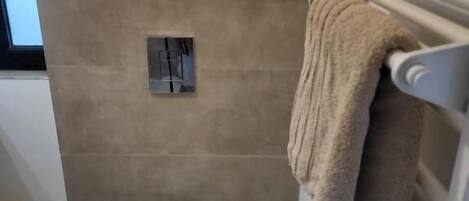 Un baño con inodoro, toallero y radiador.