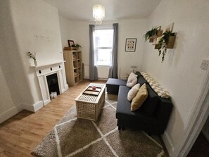 A living room with a fireplace, a sofa, a coffee table, and a rug. - Central Angel Location: 1BR Apartment (Greater London)