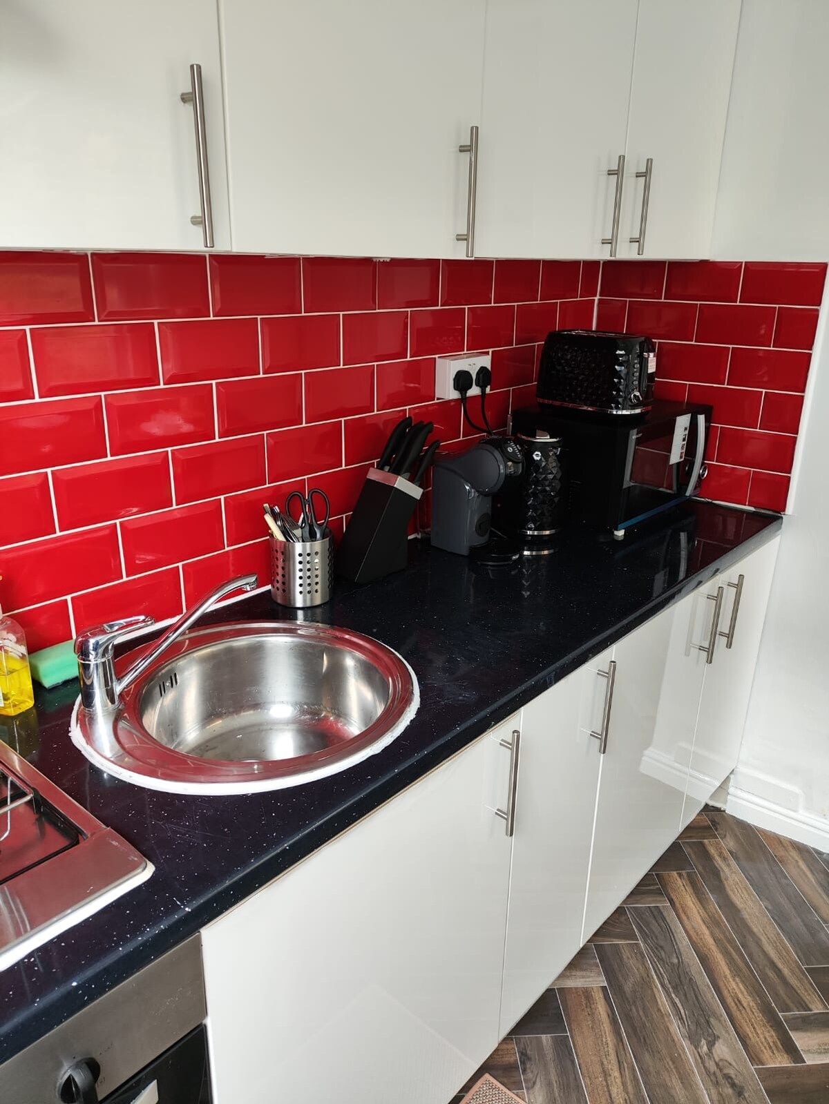 A kitchen with a stainless steel sink, a coffee maker, and a knife block.