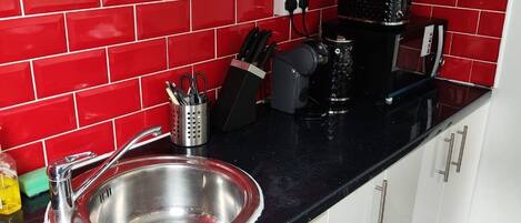A kitchen with a stainless steel sink, a coffee maker, and a knife block.