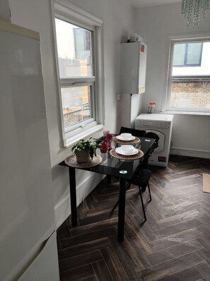 A dining area with a table set for two, a window, and a built-in washing machine. - Central Angel Location: 1BR Apartment (Greater London)