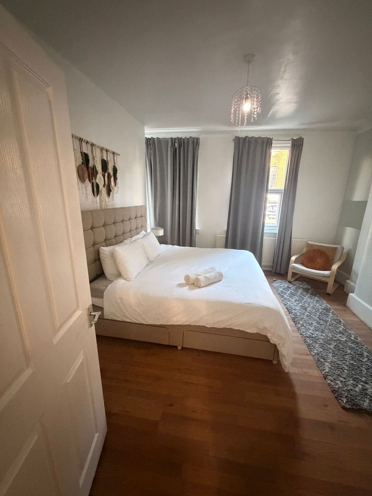 Een slaapkamer met een bed, een stoel, een vloerkleed en een wand met decoraties.
