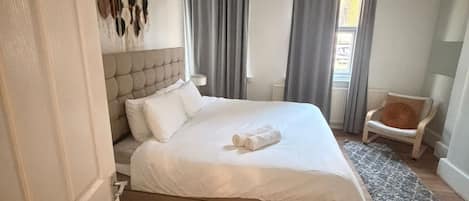 A bedroom with a bed, a chair, a rug, and a wall with hanging decorations.