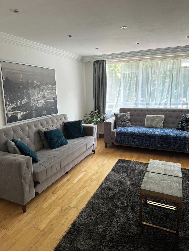 A living room with two sofas, a coffee table, and a large window with curtains.