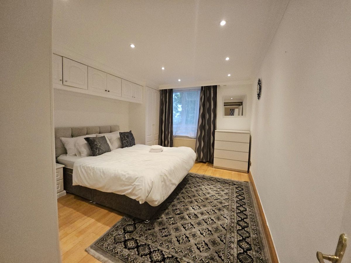 A bedroom with a bed, bedside tables, a dresser, and a patterned rug.