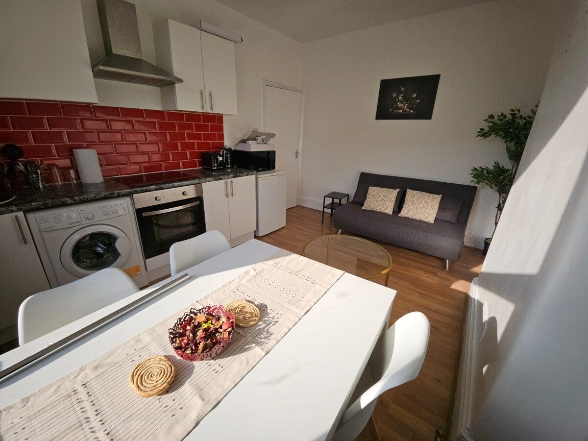 A compact living space with a kitchenette, a dining area, and a sofa.