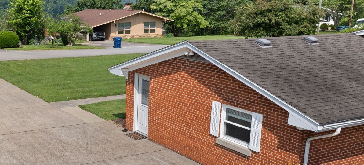 A single-story brick house with a sloped roof, a front door, and a small window.