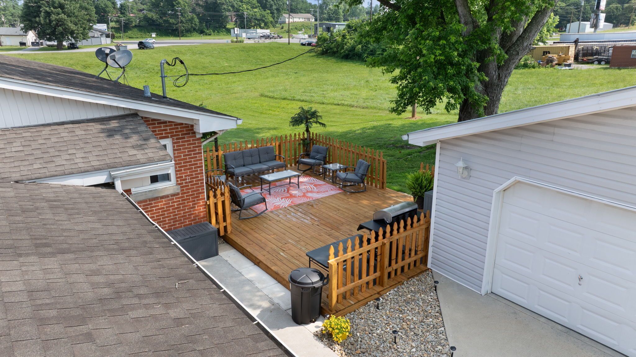 A backyard with a wooden deck, outdoor furniture, and a garage.