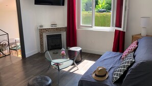 Habitació moderna amb llar de foc, llit, televisió i vista a un jardí.