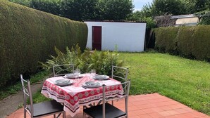 Terrassa a l'exterior amb una taula preparada per a quatre persones, envoltada de cadires metàl·liques.
