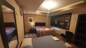 A hotel room with a large bed, a smaller bed, a desk, and a chair. There is a painting on the wall and a window with a view. - Hotel Naciuonal (Sobral)