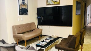 A living room with a sofa, armchairs, a coffee table, a TV, and artwork on the walls. - Hotel Naciuonal (Sobral)