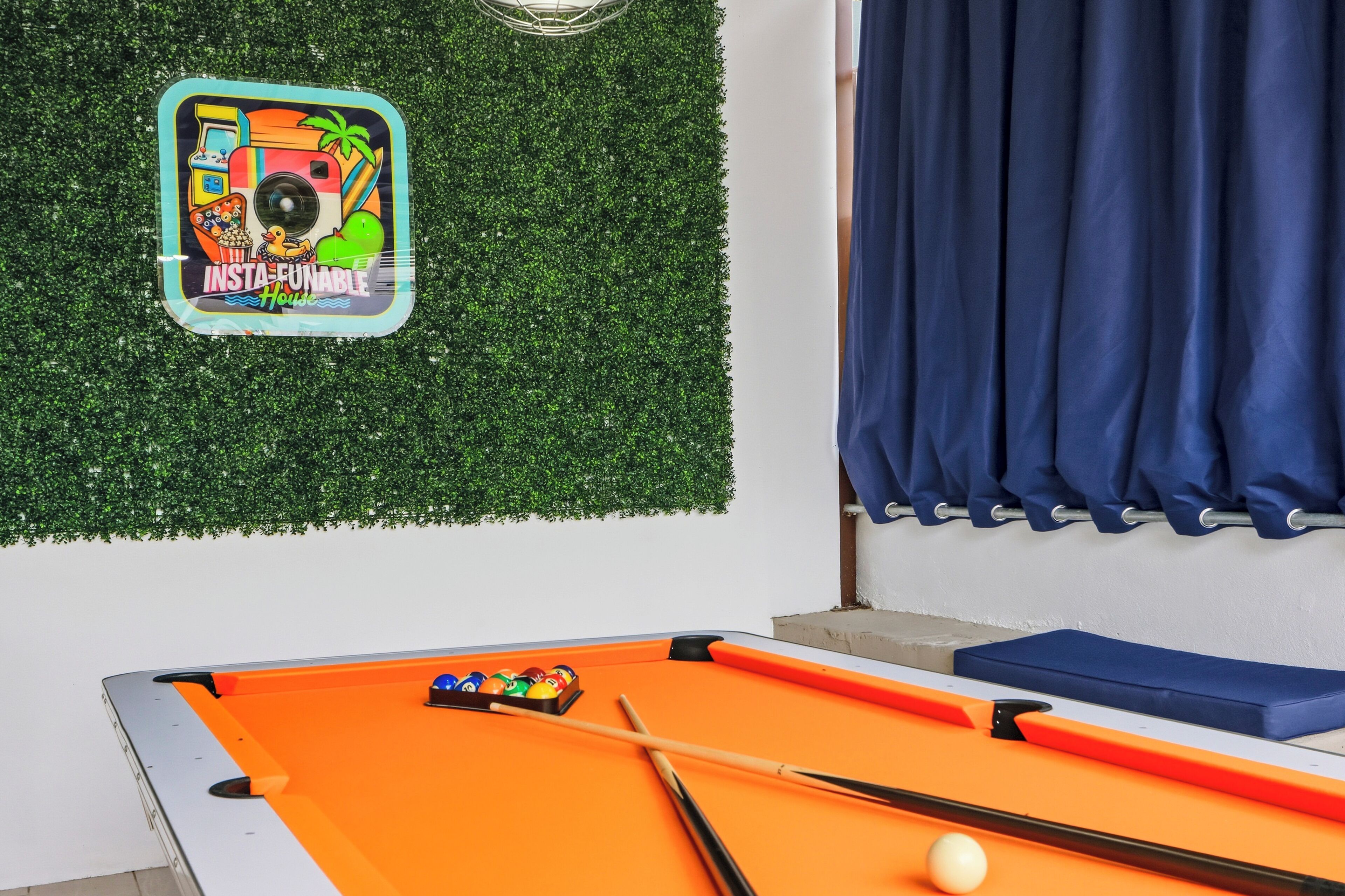 A pool table with a colorful sticker, a blue curtain, and a green wall.