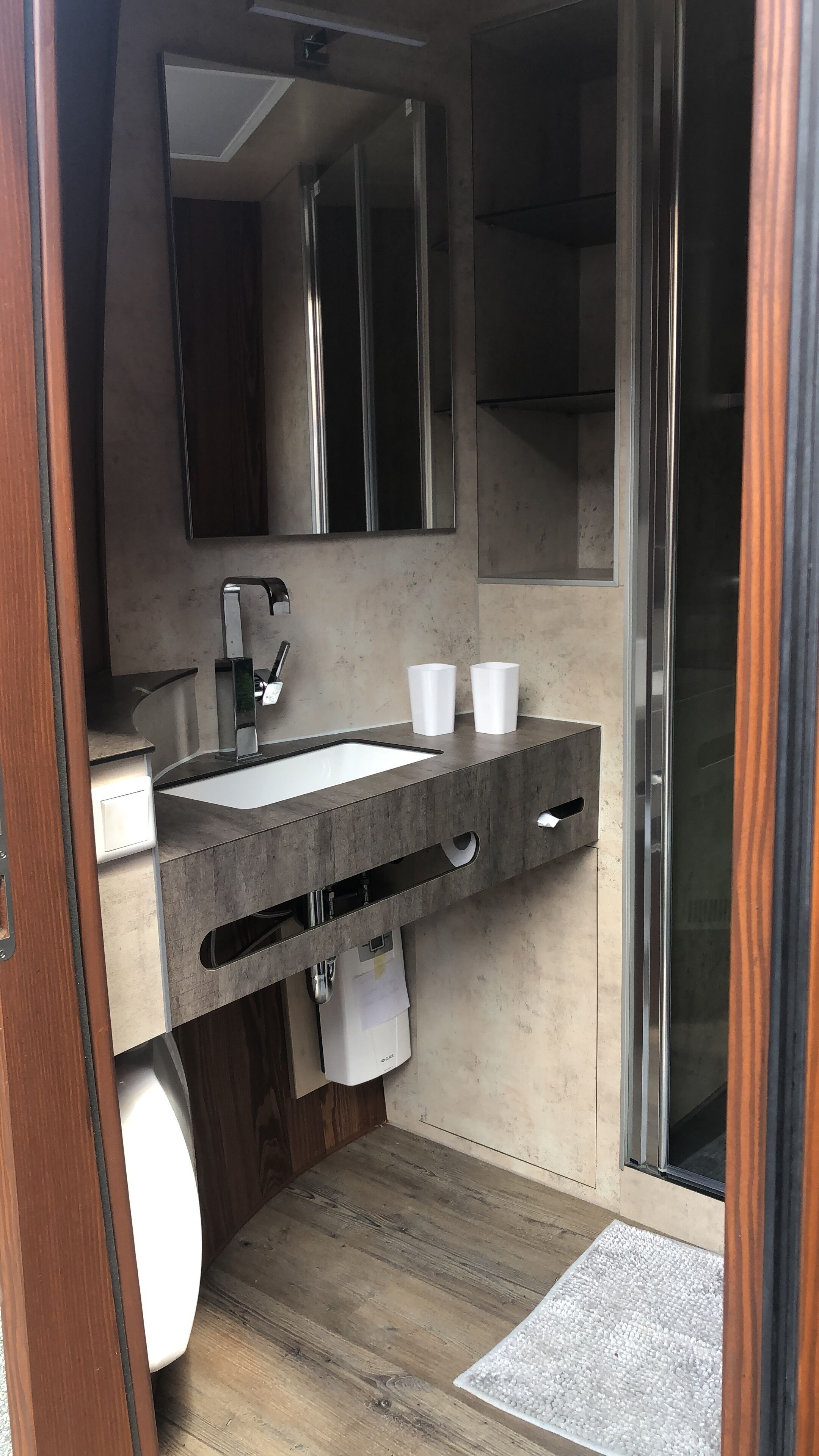 Un bagno moderno con uno specchio grande, un lavandino, due tazze bianche e un distributore di asciugamani.