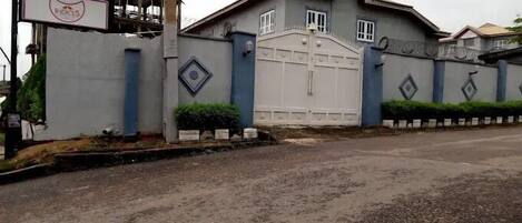 A large, gated building with a prominent entrance and a signboard.