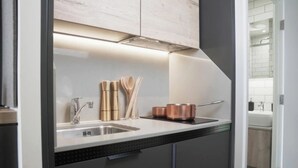 Una cucina moderna con lavello in acciaio inox, pentole in rame e utensili in legno.