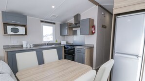 A compact kitchen with a microwave, stove, and refrigerator. - Manor House Platinum 3 Bedroom (Maryport)