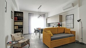 A modern living room with a sofa, a chair, a small table, and a bookshelf. - Modern House near Trastevere (Roma)
