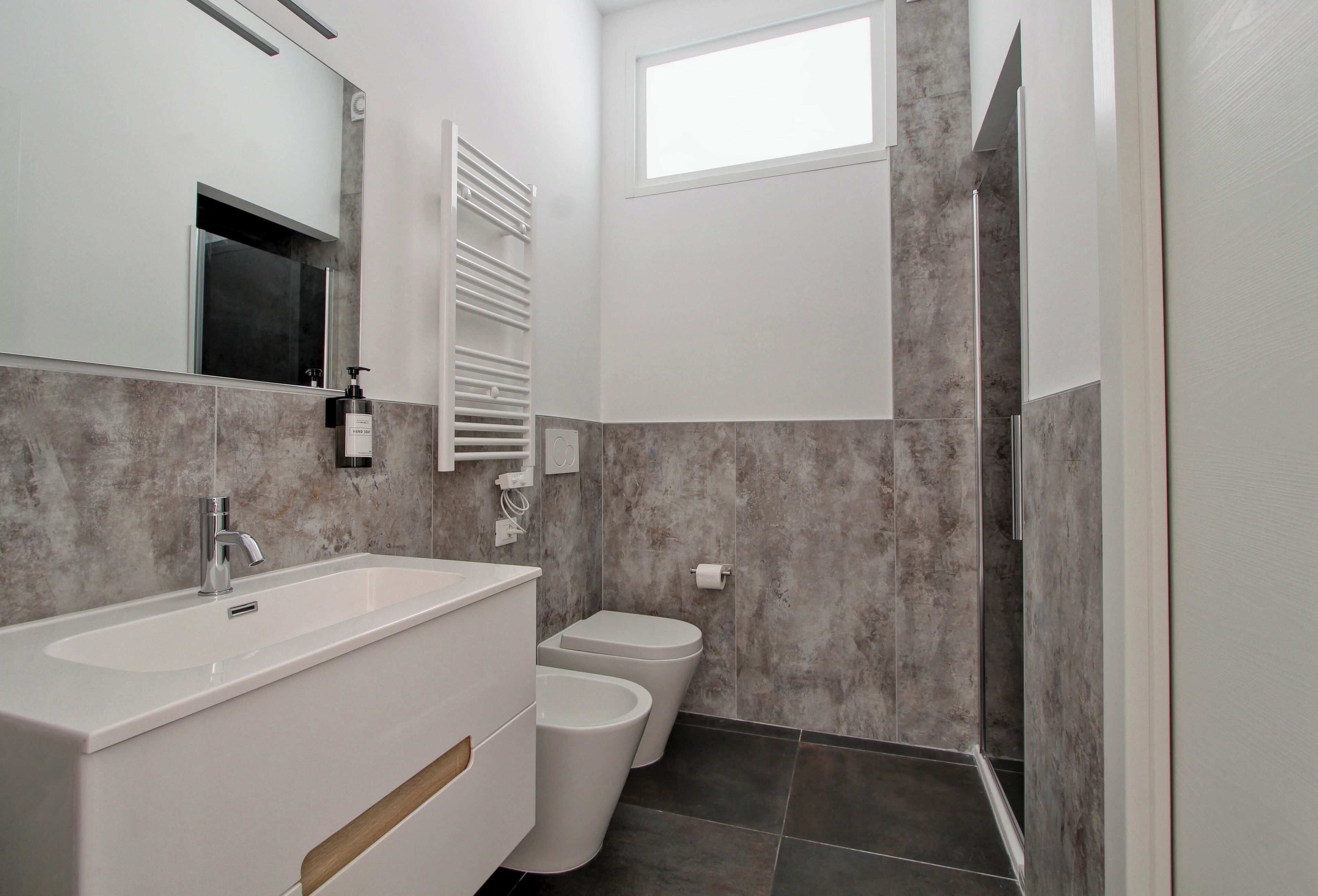 A modern bathroom with a white vanity, a toilet, and a shower area.