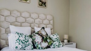 A bed with a green velvet throw, white bedding, and floral-patterned pillows.