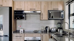 A modern kitchen with wooden cabinets, stainless steel appliances, a built-in oven, microwave, and a washing machine.