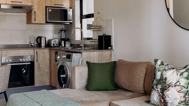 A compact living space with a kitchenette, a sofa, a coffee table, and a patterned rug.