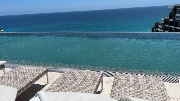 Ein Poolbereich mit Liegestühlen und Blick auf den Ozean.