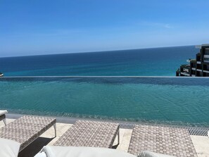 Un espace aménagé au bord de la piscine, avec des chaises longues et une vue sur l’océan.