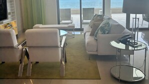 Ein modernes Wohnzimmer mit einem großen Schiebeglasfenster, das auf einen Balkon mit Meerblick führt.