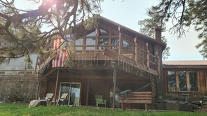 Une cabane en bois dotée d’un balcon, d’un porche couvert et d’une cour gazonnée.