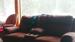 Un canapé en cuir marron, accompagné d’un pouf assorti et d’un plaid aux couleurs vives.