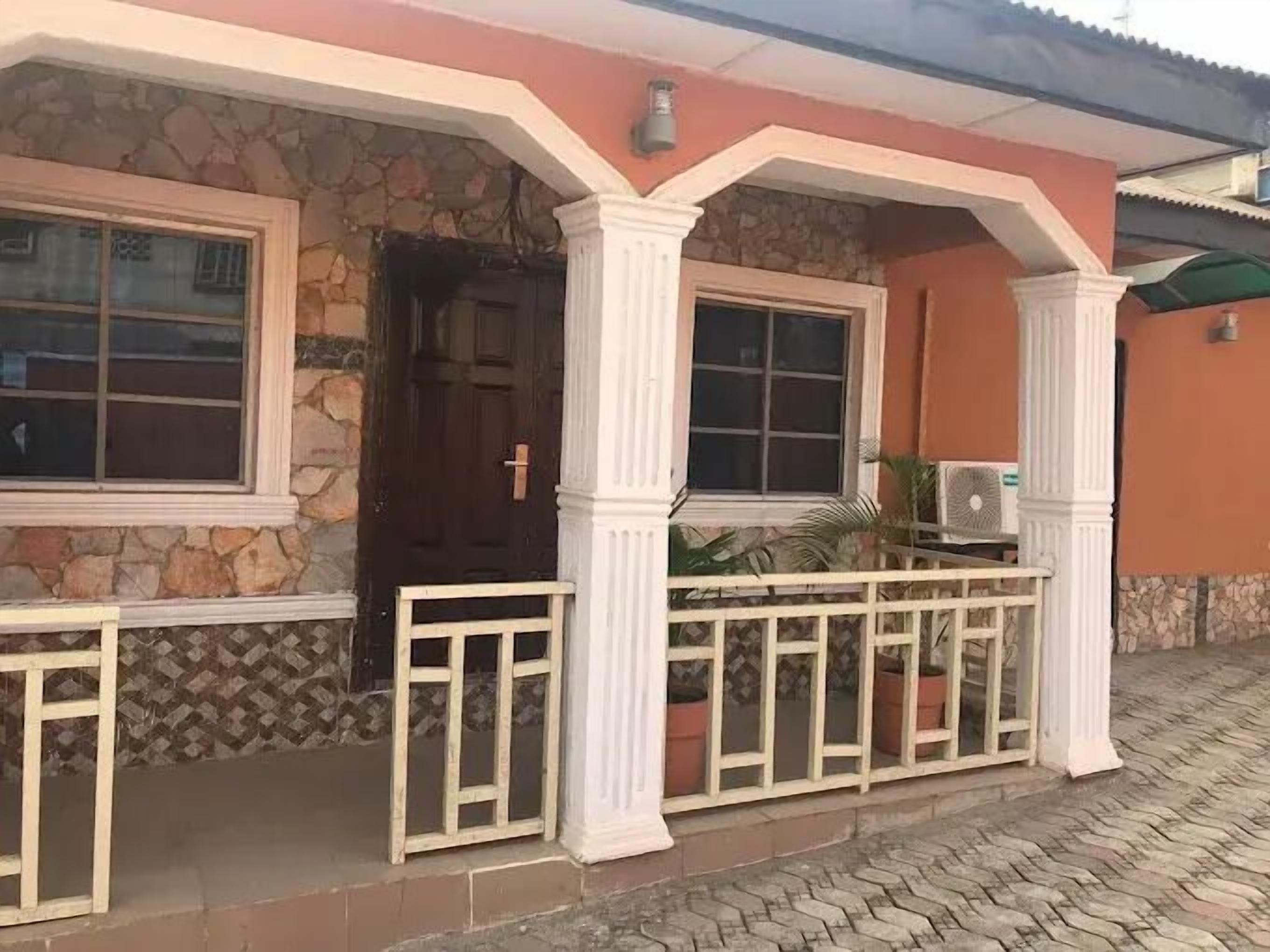 A house with a stone facade, a wooden door, and a balcony with a white railing.