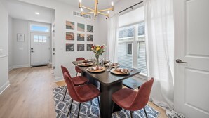 A dining area with a dark wooden table, red chairs, and a chandelier. - Hot Tub - Mins to Short North - Retro Game Room - New Construction (Columbus)