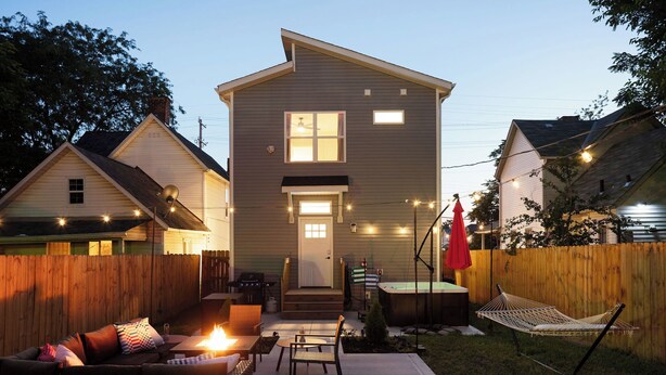 A two-story house with a covered patio area featuring a sofa, chairs, and a small table. - Hot Tub - Mins to Short North - Retro Game Room - New Construction (Columbus)