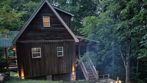 A wooden cabin with a fire pit in the foreground. - Cozy Cabin (Burnside)