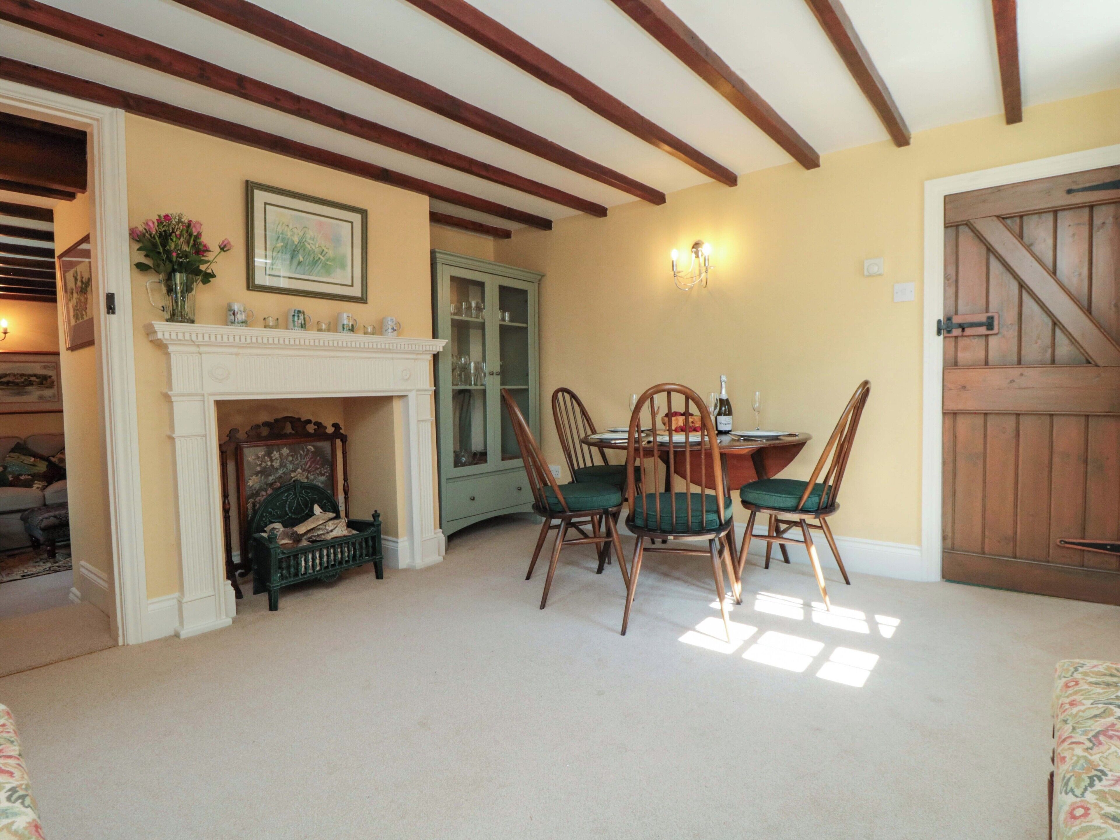 A dining area with a fireplace, a green cabinet, and a wooden door.
