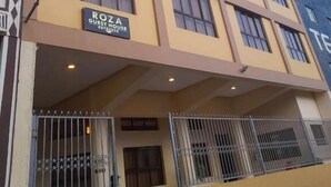 Un edificio de varios pisos con un letrero que dice “ROZA GUEST HOUSE”, indicando una residencia para huéspedes.