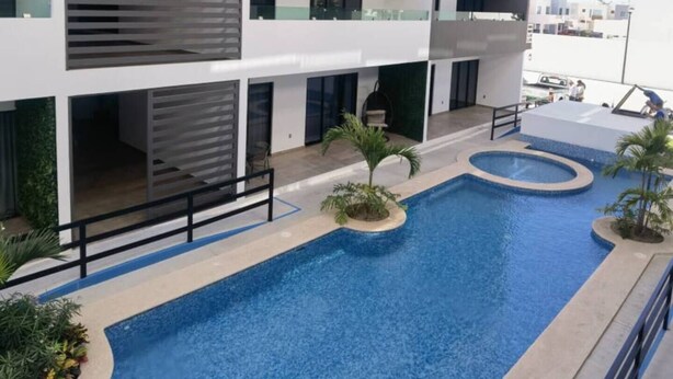 Ein mehrstöckiges Gebäude mit Schwimmbad, Balkonen und modernem architektonischem Design.