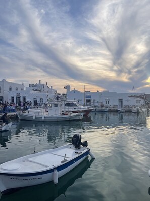Marina com barcos atracados, um edifício branco com uma cruz no topo e uma multidão de pessoas.