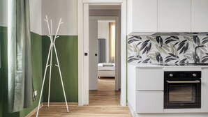 A modern kitchen with white cabinets, a black oven, and a backsplash with a leaf pattern. - Navigli Riverside - One Bedroom Apartment, Sleeps 4 (Milano)