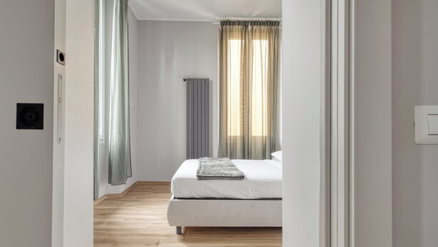A bedroom with a bed, a radiator, and a window with curtains. - Navigli Riverside - One Bedroom Apartment, Sleeps 4 (Milano)