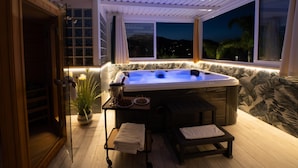A hot tub with a wooden deck, a table with a plant and a glass, and a view of the night sky. - Villa Amira - Castellammare Del ... (Castellammare del golfo)