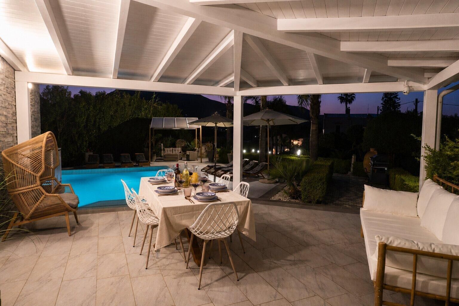 Une terrasse extérieure avec une piscine, une table à manger, des chaises et des fauteuils de relaxation.