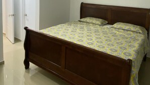 Un dormitorio con una cama de madera, una puerta blanca y un equipo de aire acondicionado en la pared.