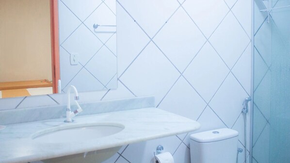 Une salle de bain avec un lavabo blanc, un miroir et un espace douche.
